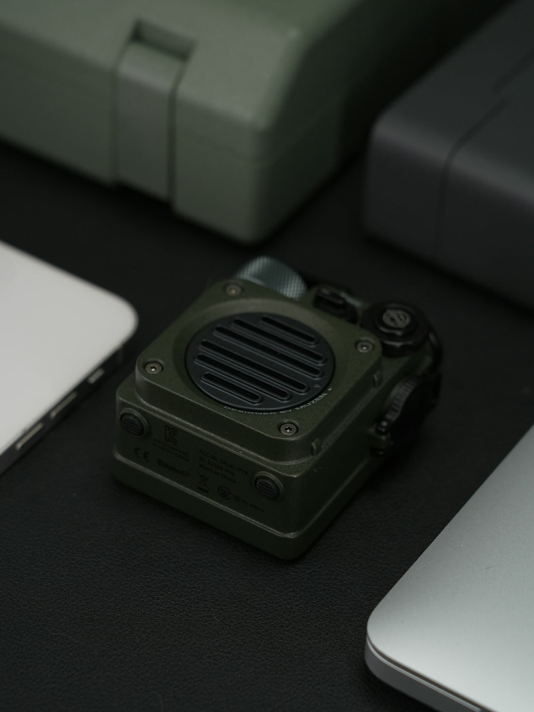 A green speaker is centered with several gadgets.